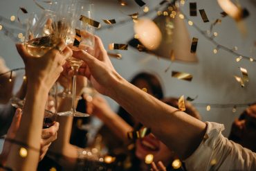 Amis qui trinquent au champagne sous une pluie de confettis dorés pour le réveillon du Nouvel An à Bordeaux
